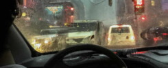 AI Image - Realistic image of a man driving a car in the streets of New York looking through the window and seeing the rain outside in a heavy traffic.