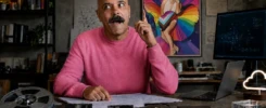 Imagem criada com inteligência artificial mostrando Régis Araújo em um ambiente que mistura tecnologia, arte e memória analógica. Cercado por disquetes, HDs antigos, computador e referências visuais pop e LGBTQIAPN+, ele aparece em pose reflexiva e bem-humorada, simbolizando alguém que envelheceu acompanhando diferentes eras da tecnologia, mas manteve intactas a curiosidade, a criatividade e a vontade de aprender.